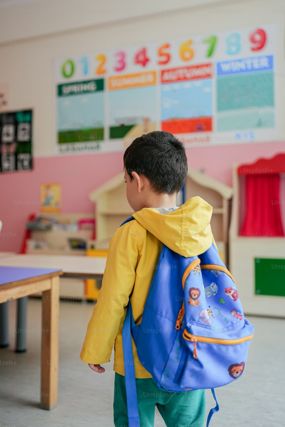 Ein kleiner Junge mit einem blauen Rucksack in einem Klassenzimmer
