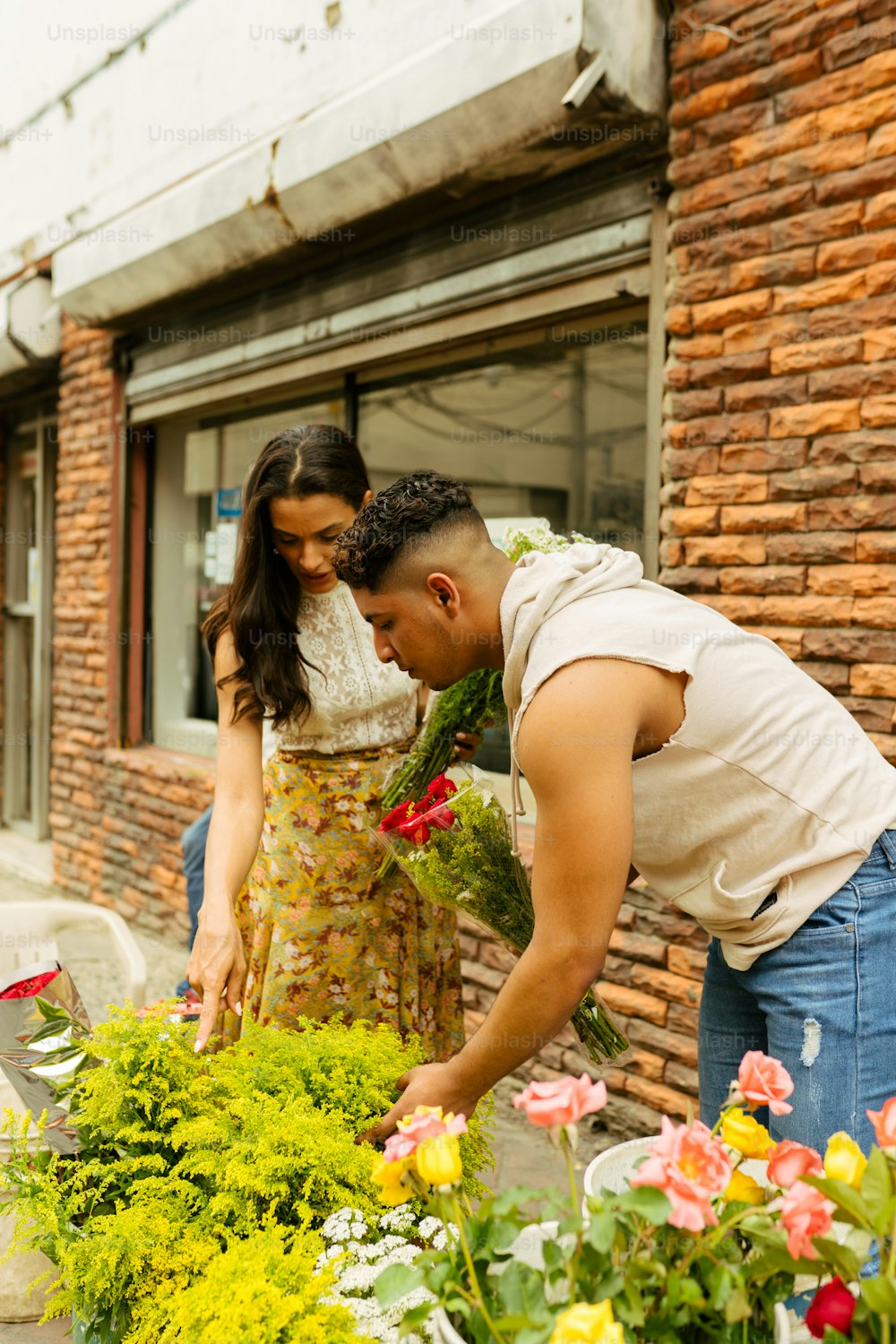 a man and a woman are looking at flowers