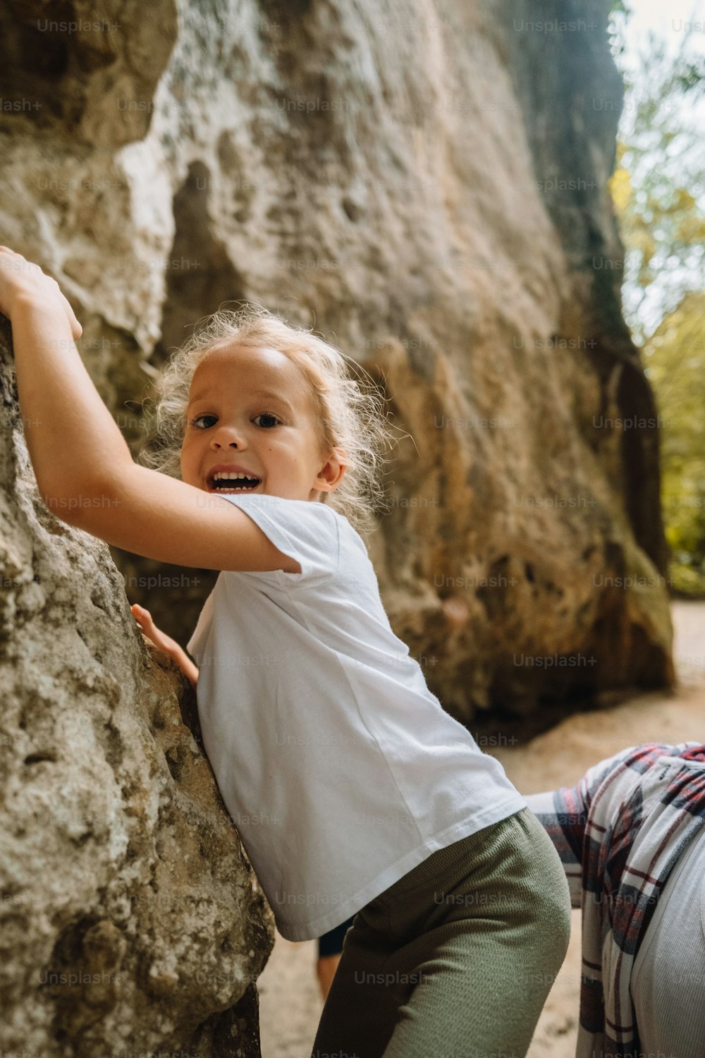 a little girl climbing up the side of a rock