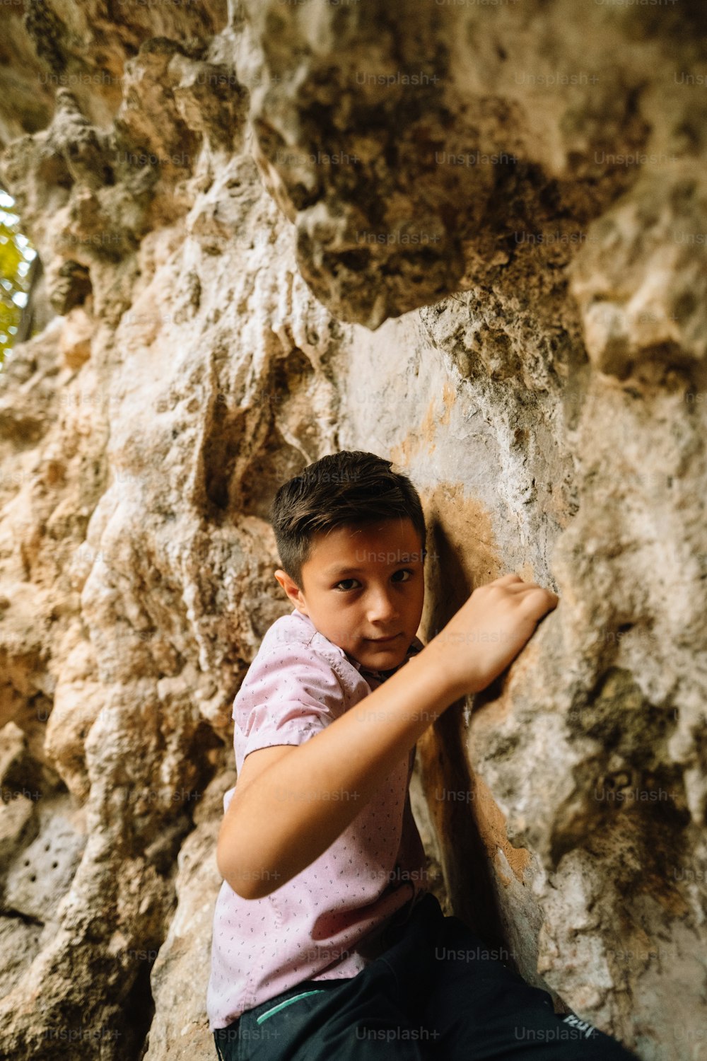 a young boy climbing up the side of a rock