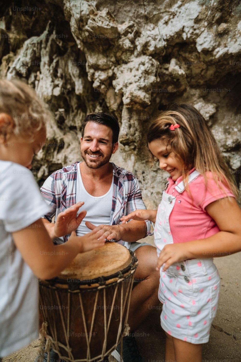 Un hombre y dos niñas tocando un tambor