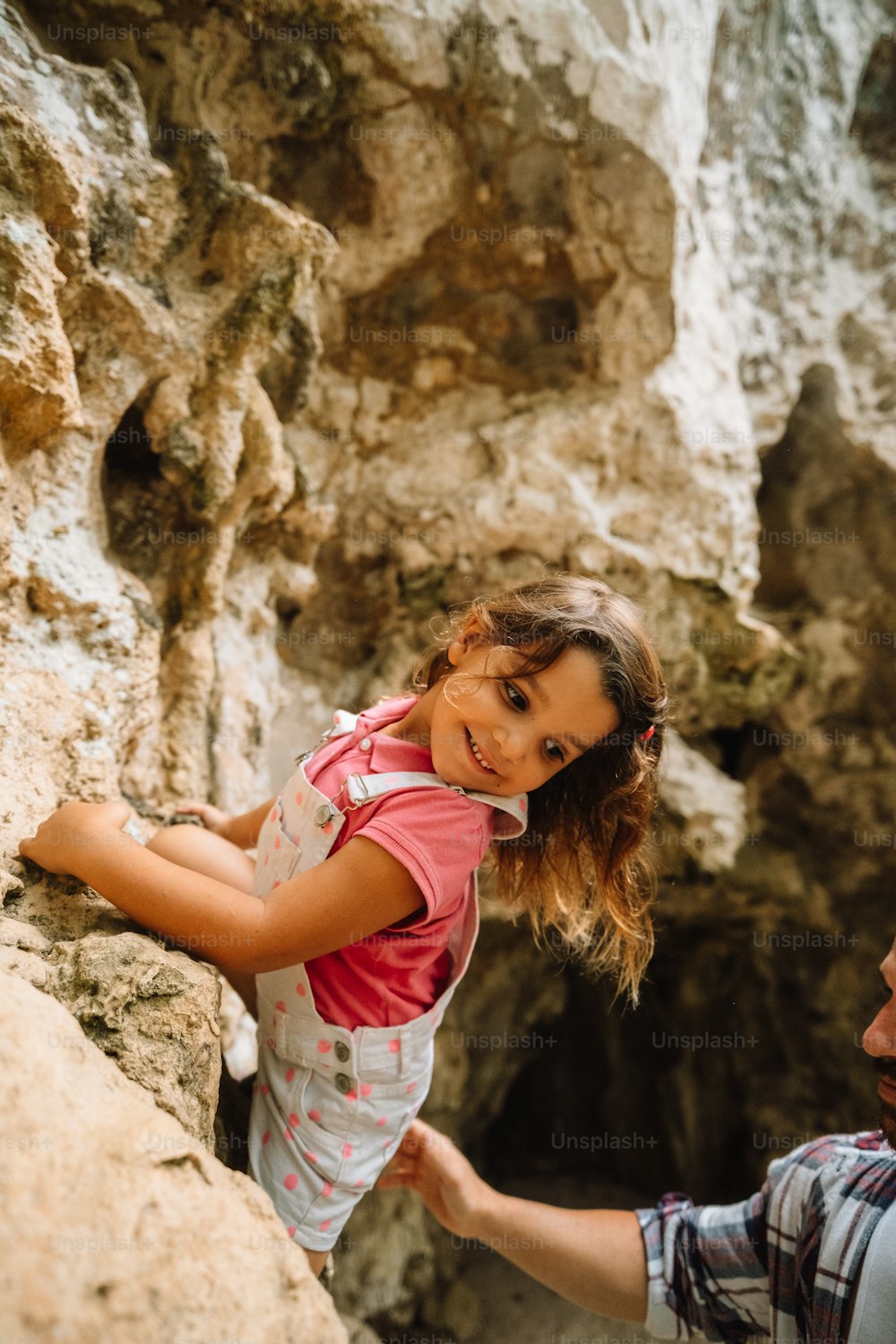 um homem segurando uma garotinha em cima de uma rocha