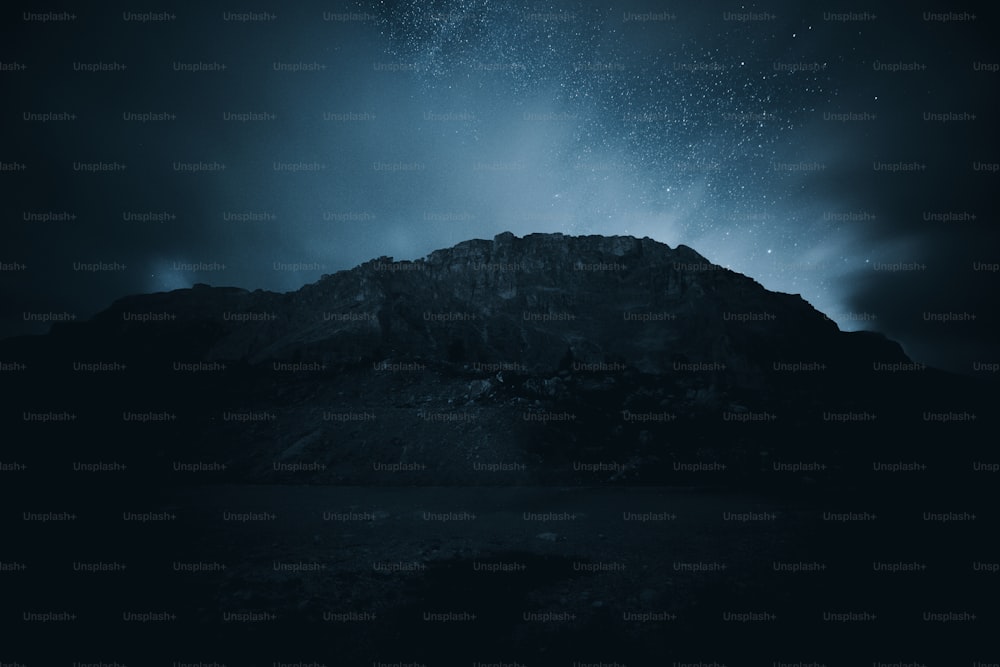 a night sky with stars above a mountain