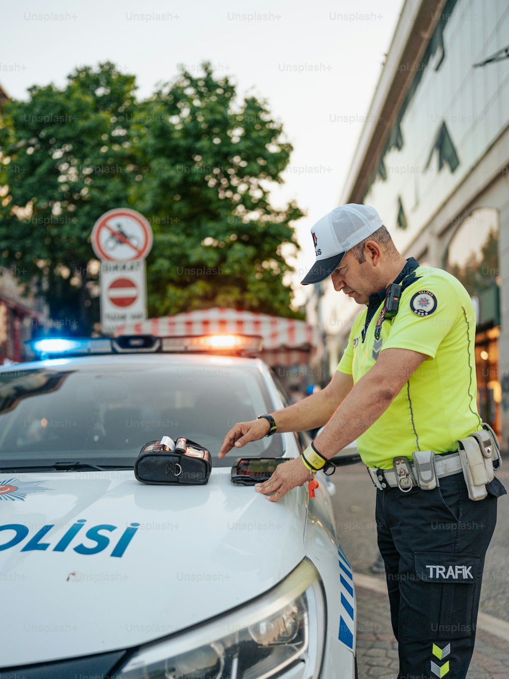 Un oficial de policía parado junto a un coche de policía