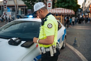 Un oficial de policía parado junto a un coche de policía