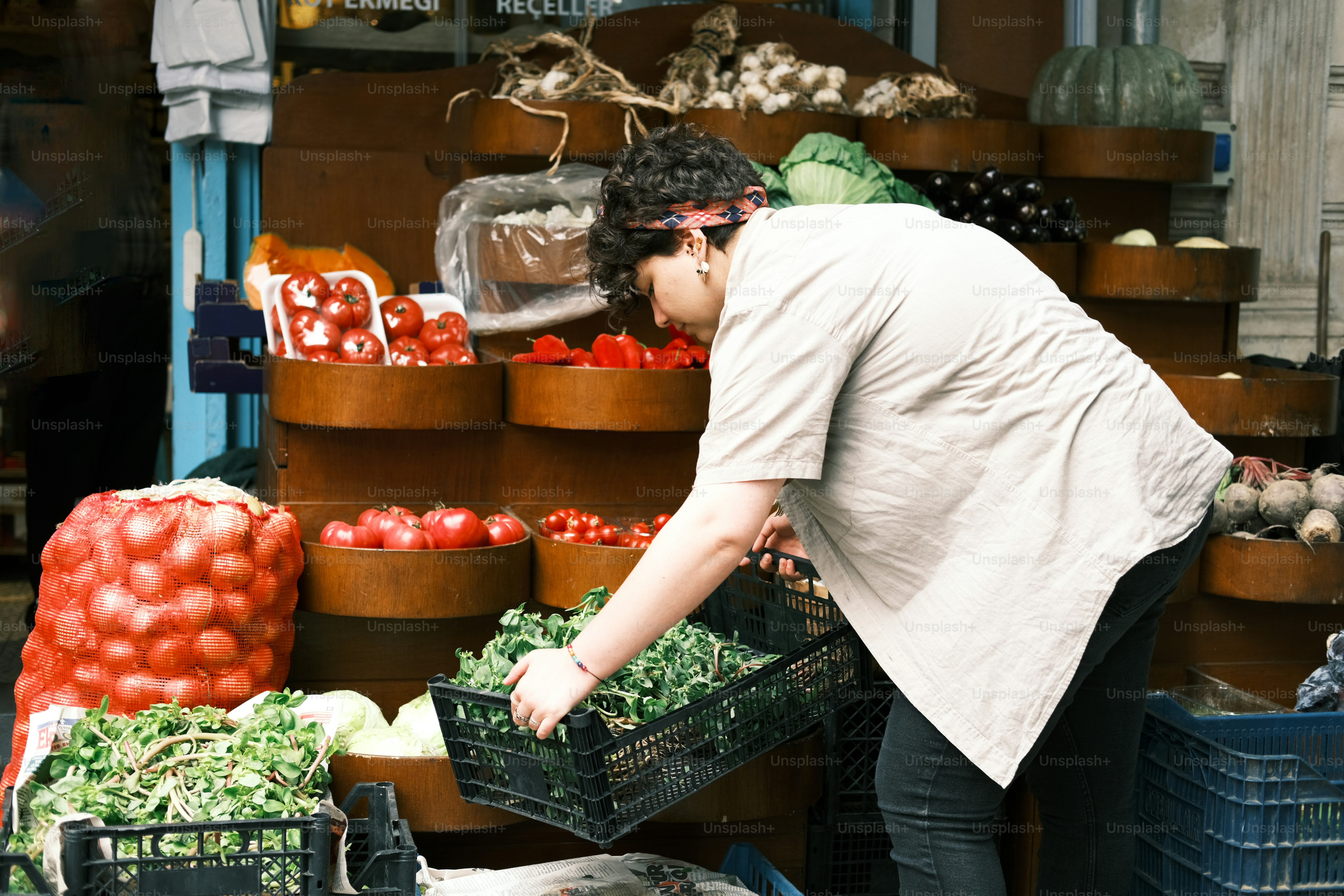 a woman is picking up vegetables at a market