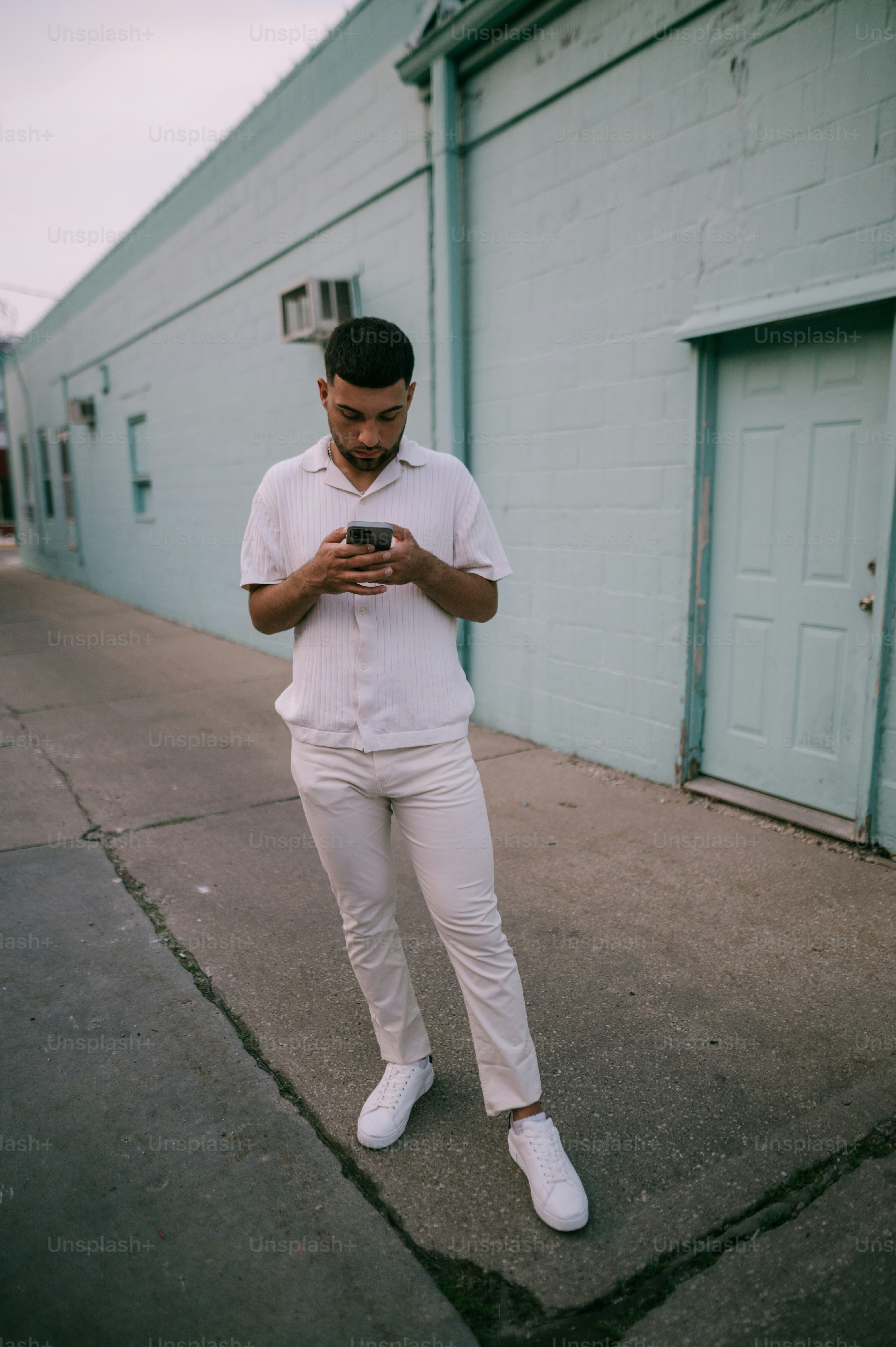 A man standing on a sidewalk looking at his cell phone photo – Gen z ...