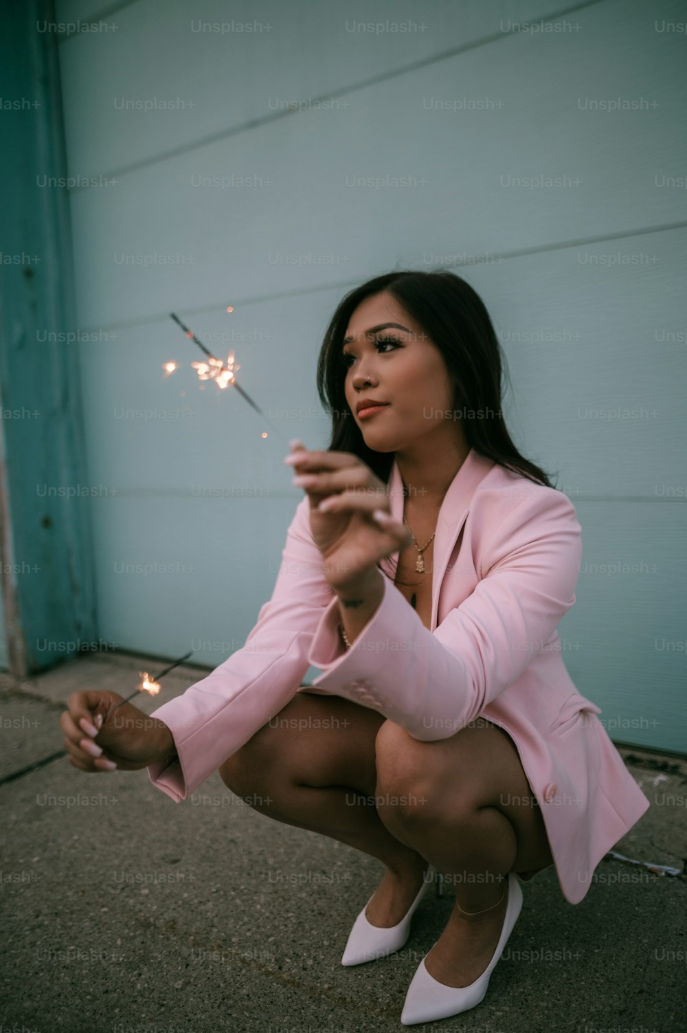 a woman in a pink suit holding a sparkler