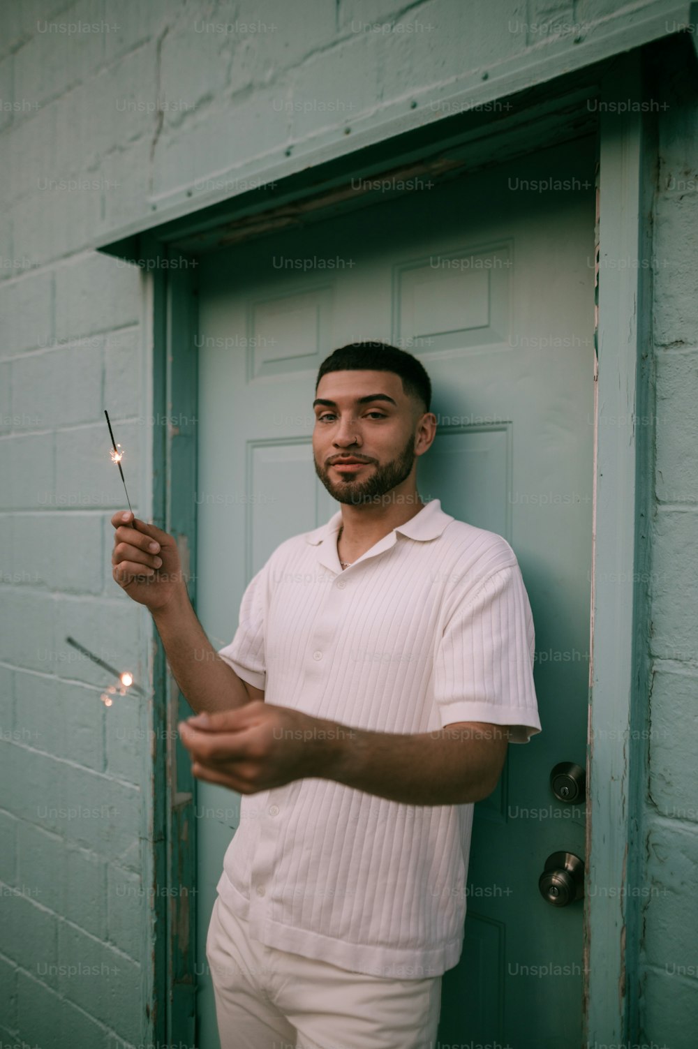 a man standing in front of a door holding a lit sparkler