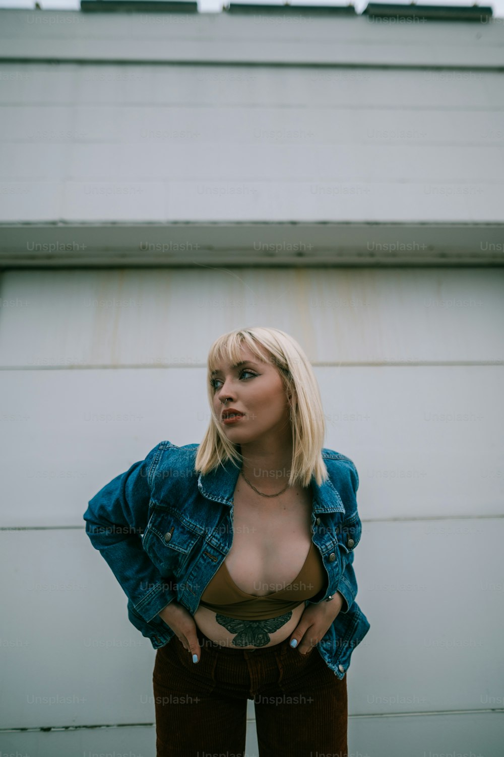 a woman wearing a denim jacket standing in front of a garage door