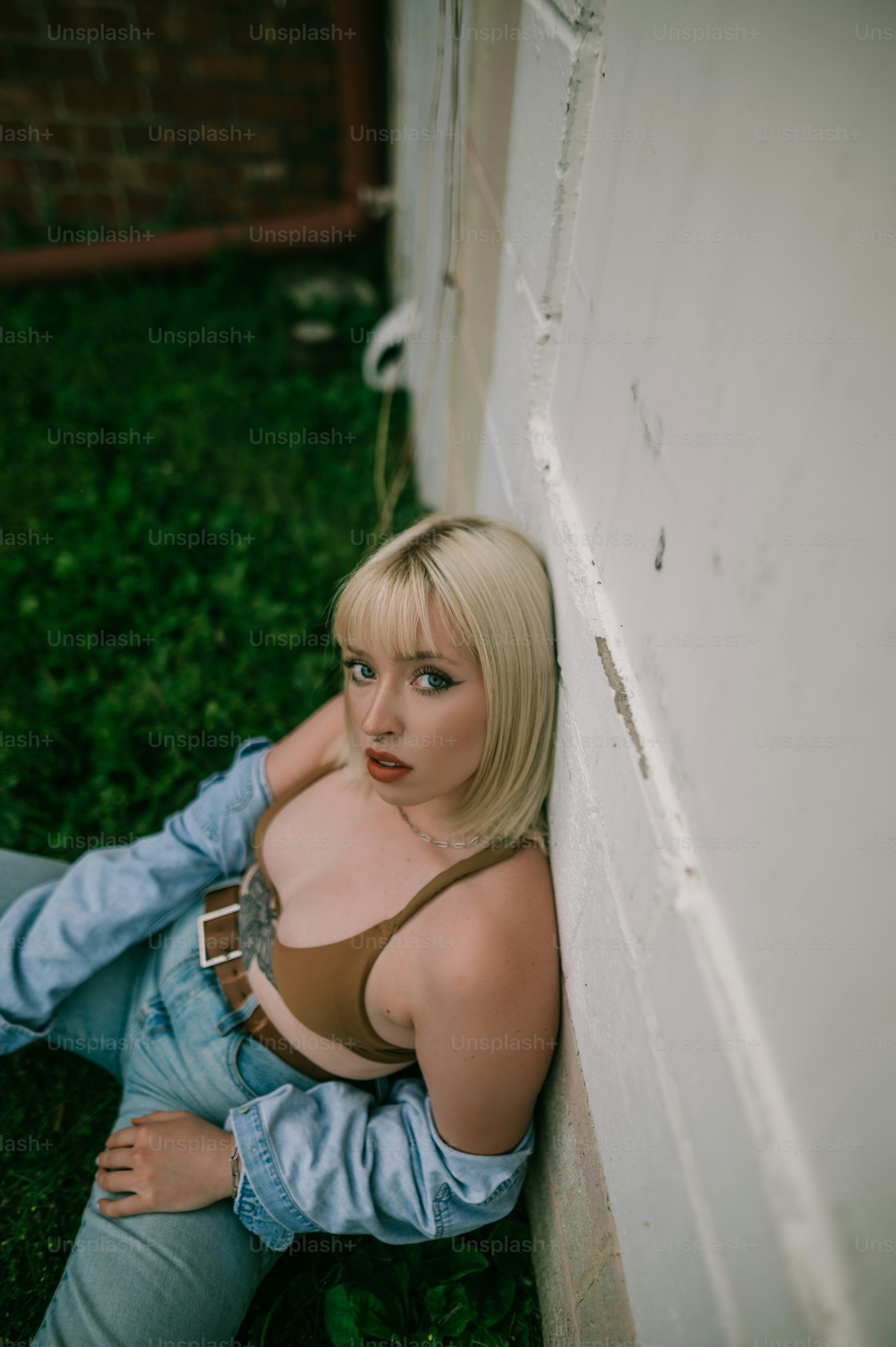 eine frau, die an einer wand sitzt und einen bh trägt