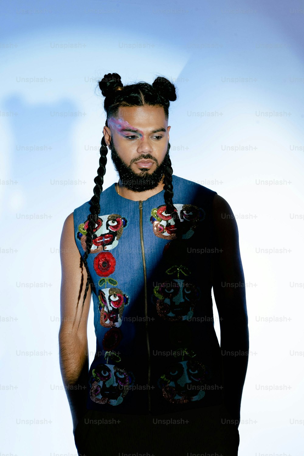 a man with braids and a blue vest