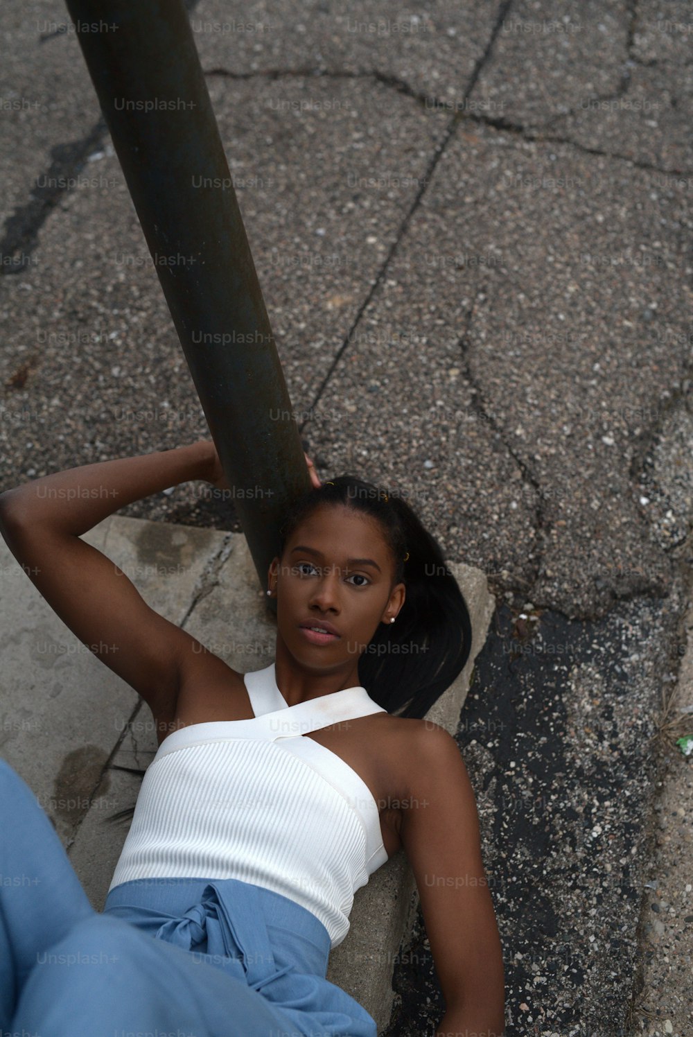 a woman laying on the ground next to a pole