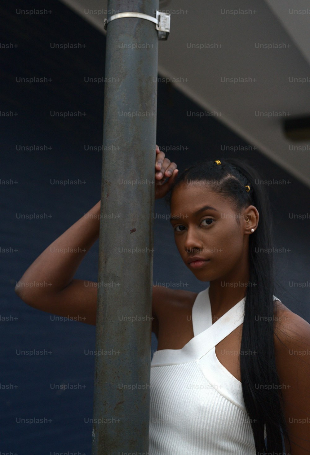 a woman with a ponytail standing next to a pole