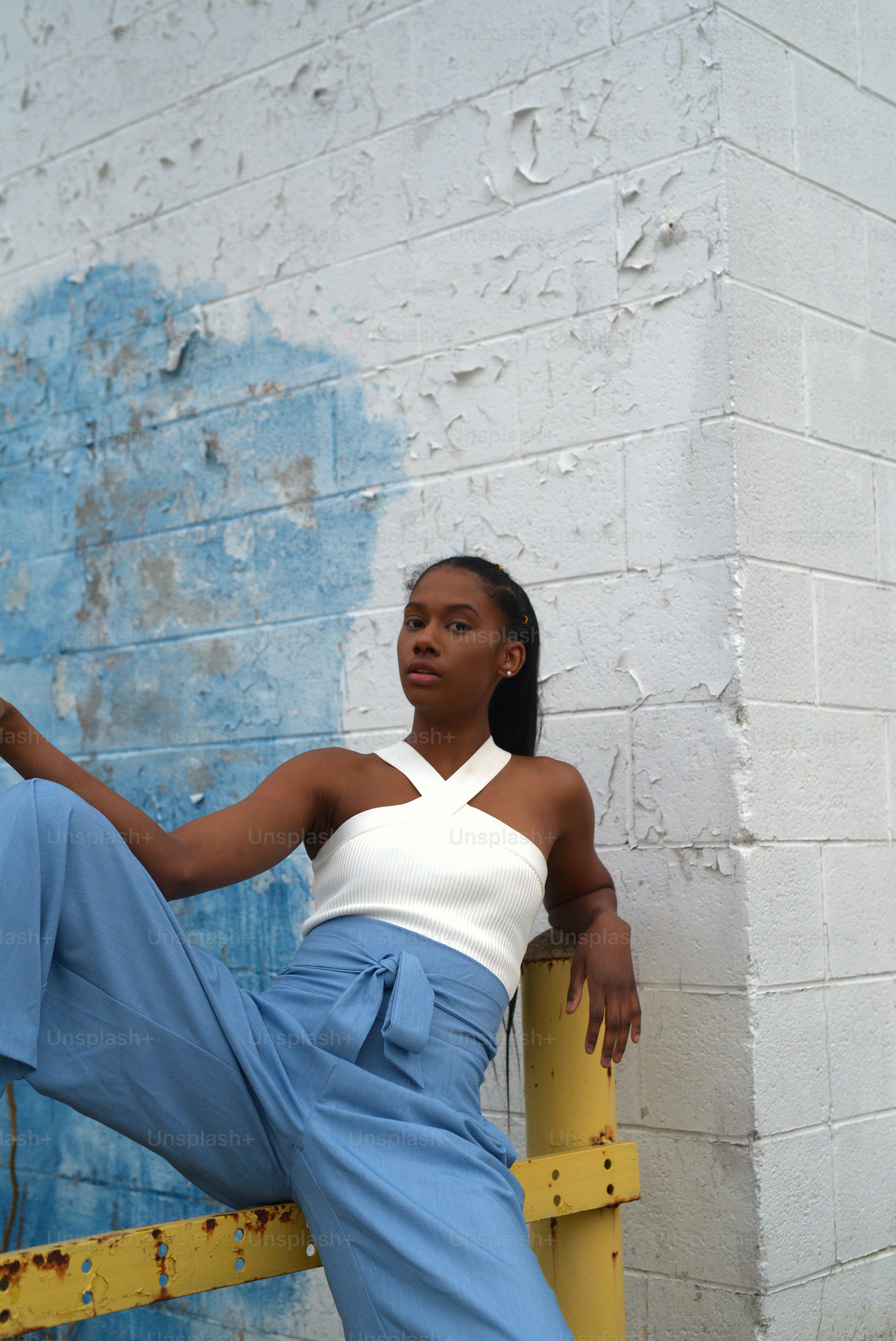 a woman leaning against a wall with her leg up