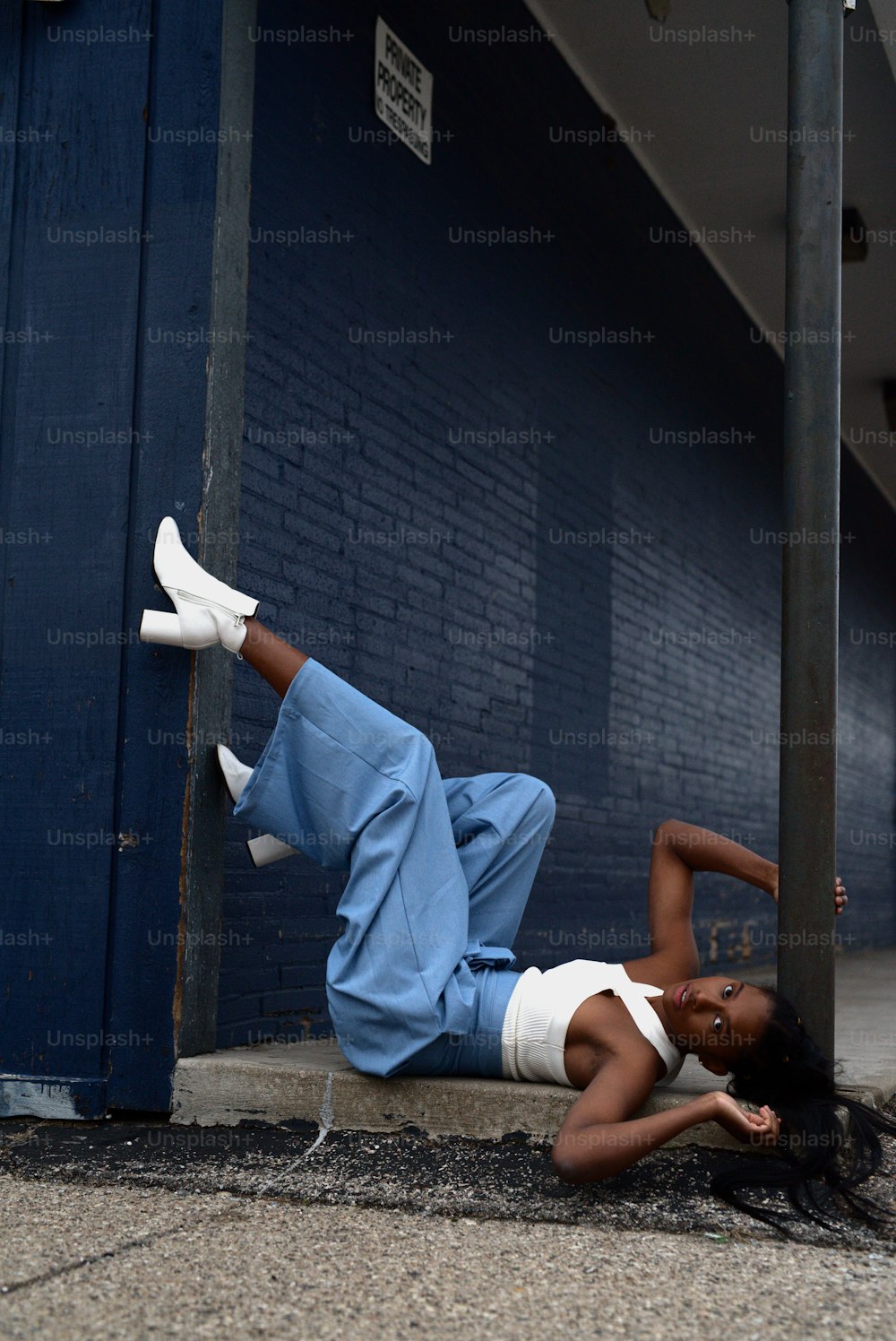 a woman laying on the ground next to a building