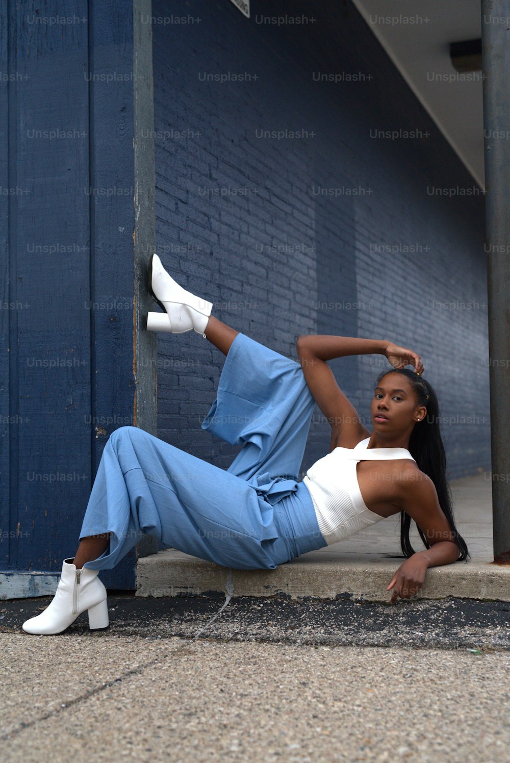 a woman leaning against a wall with her foot on the ground