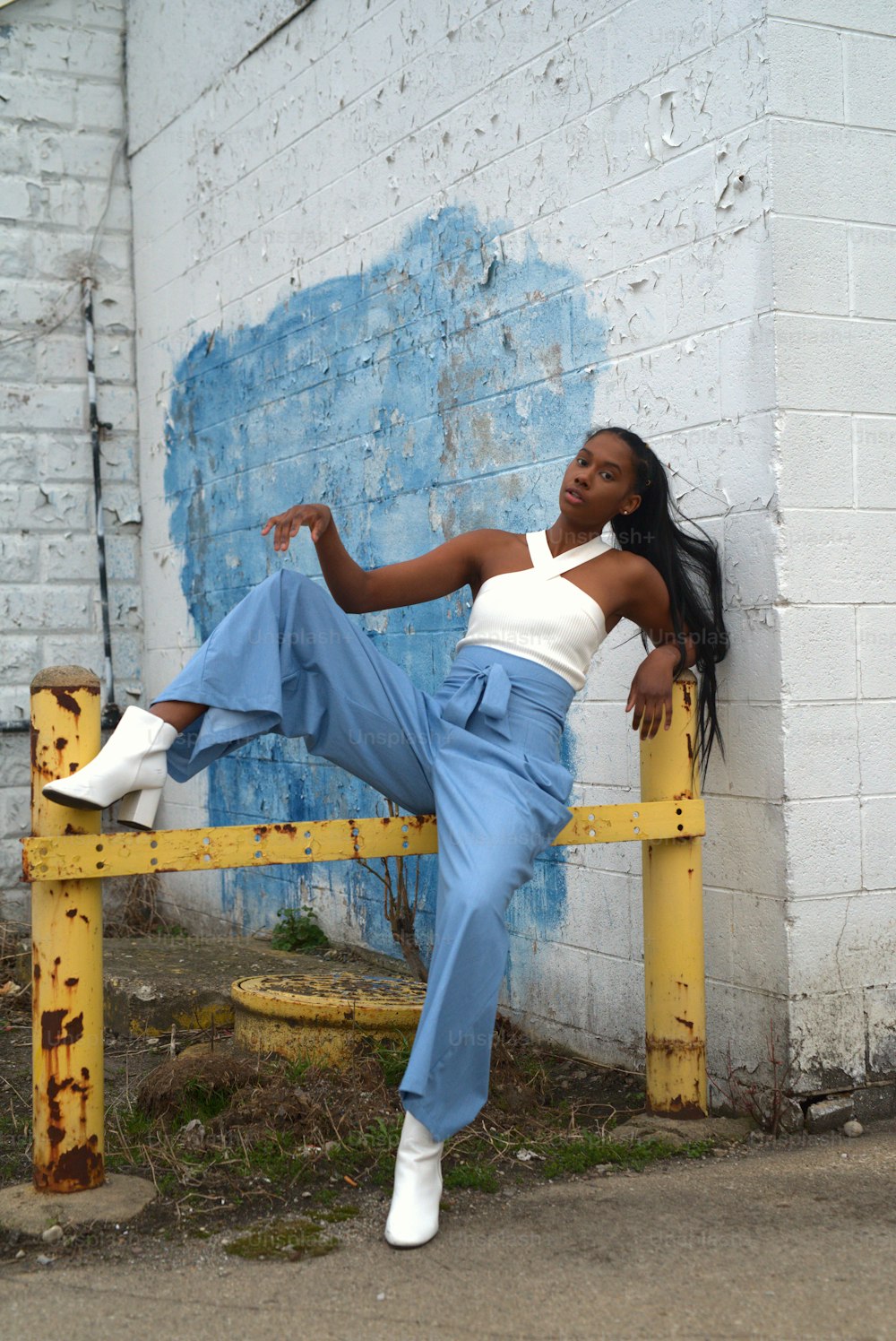 a woman leaning against a yellow rail in front of a building