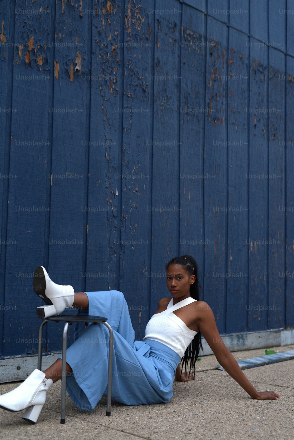a woman sitting on the ground next to a blue wall