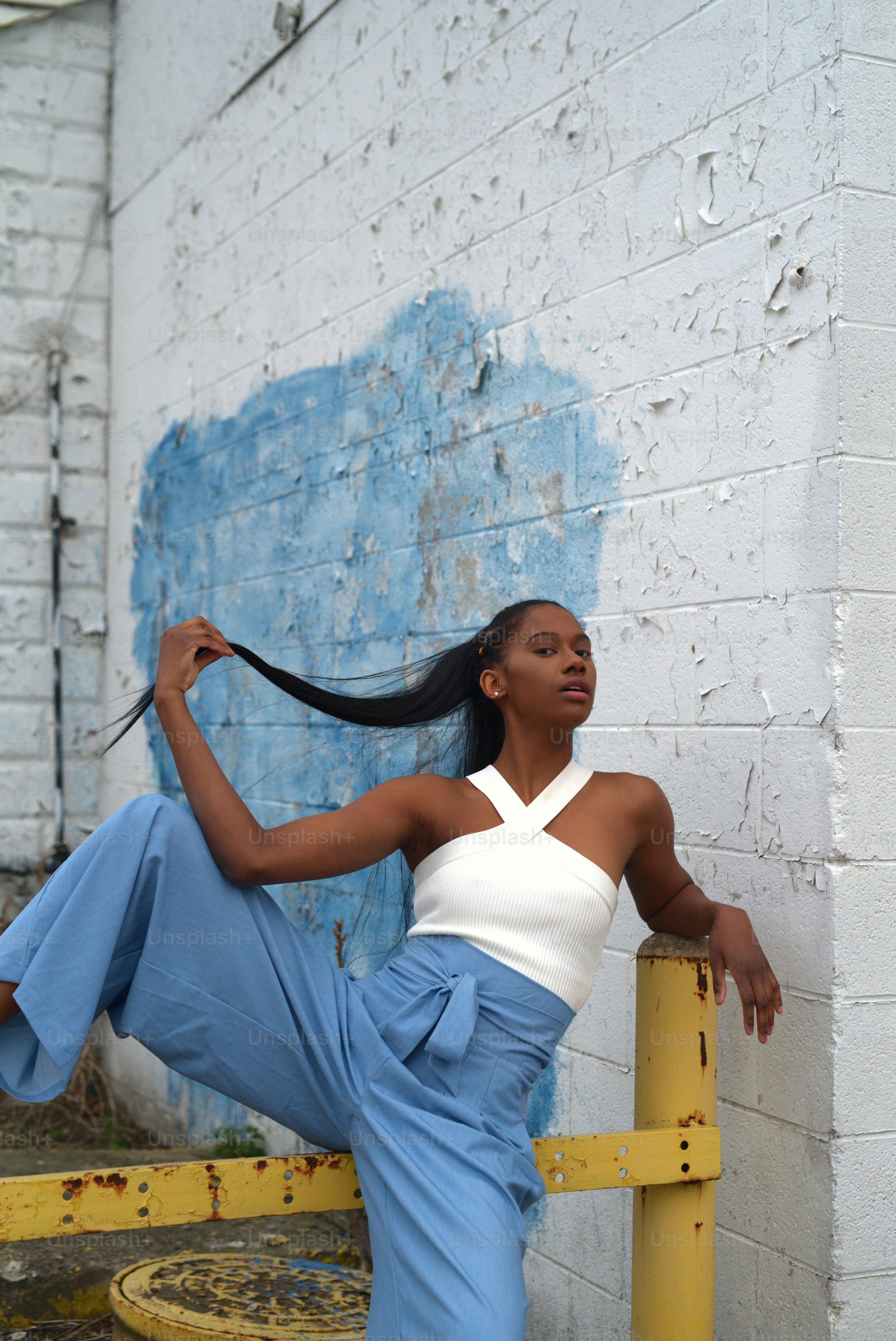 a woman leaning against a yellow rail with her hair in the air