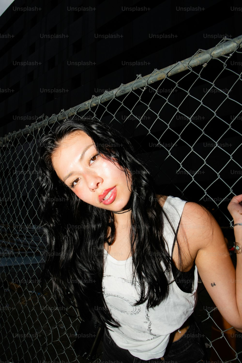 a woman standing in front of a chain link fence
