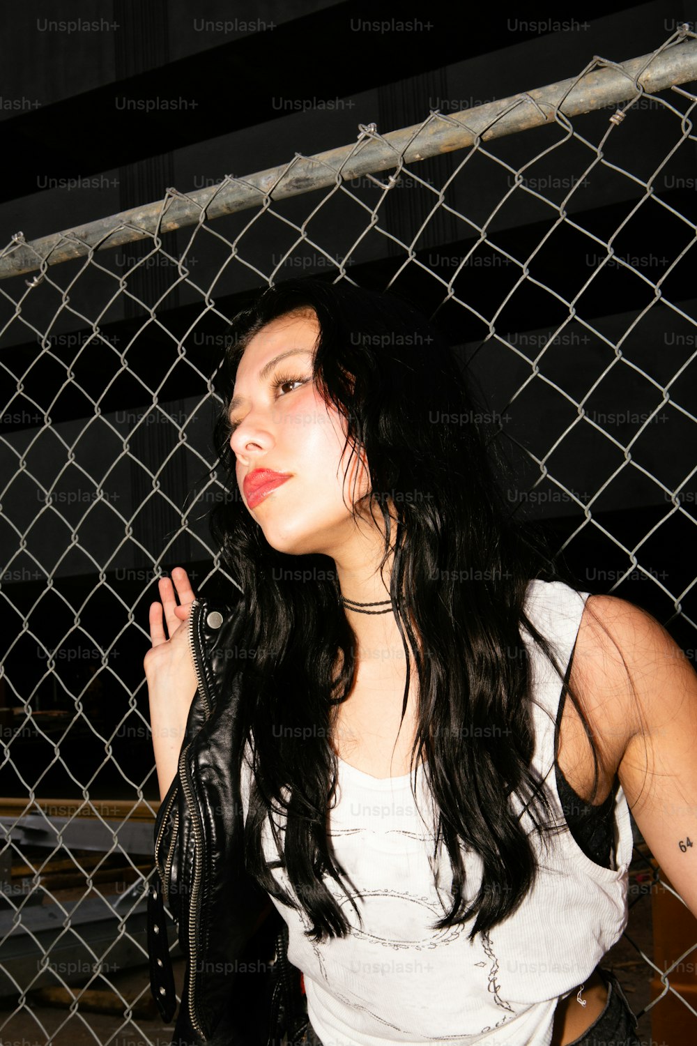 a woman standing next to a chain link fence