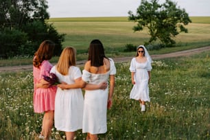 a group of women in white dresses standing in a field