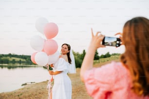 a woman taking a picture of a woman holding balloons