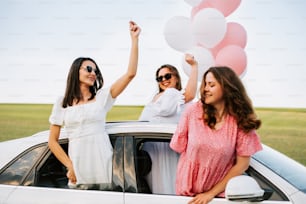 Un grupo de mujeres de pie una al lado de la otra frente a un automóvil