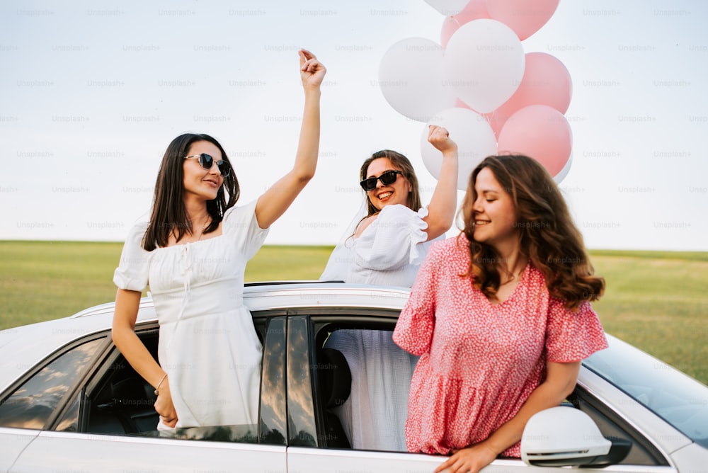 a group of women standing next to each other in front of a car