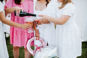 a group of women standing next to each other holding wine glasses