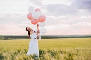 Una mujer con un vestido blanco sosteniendo un montón de globos