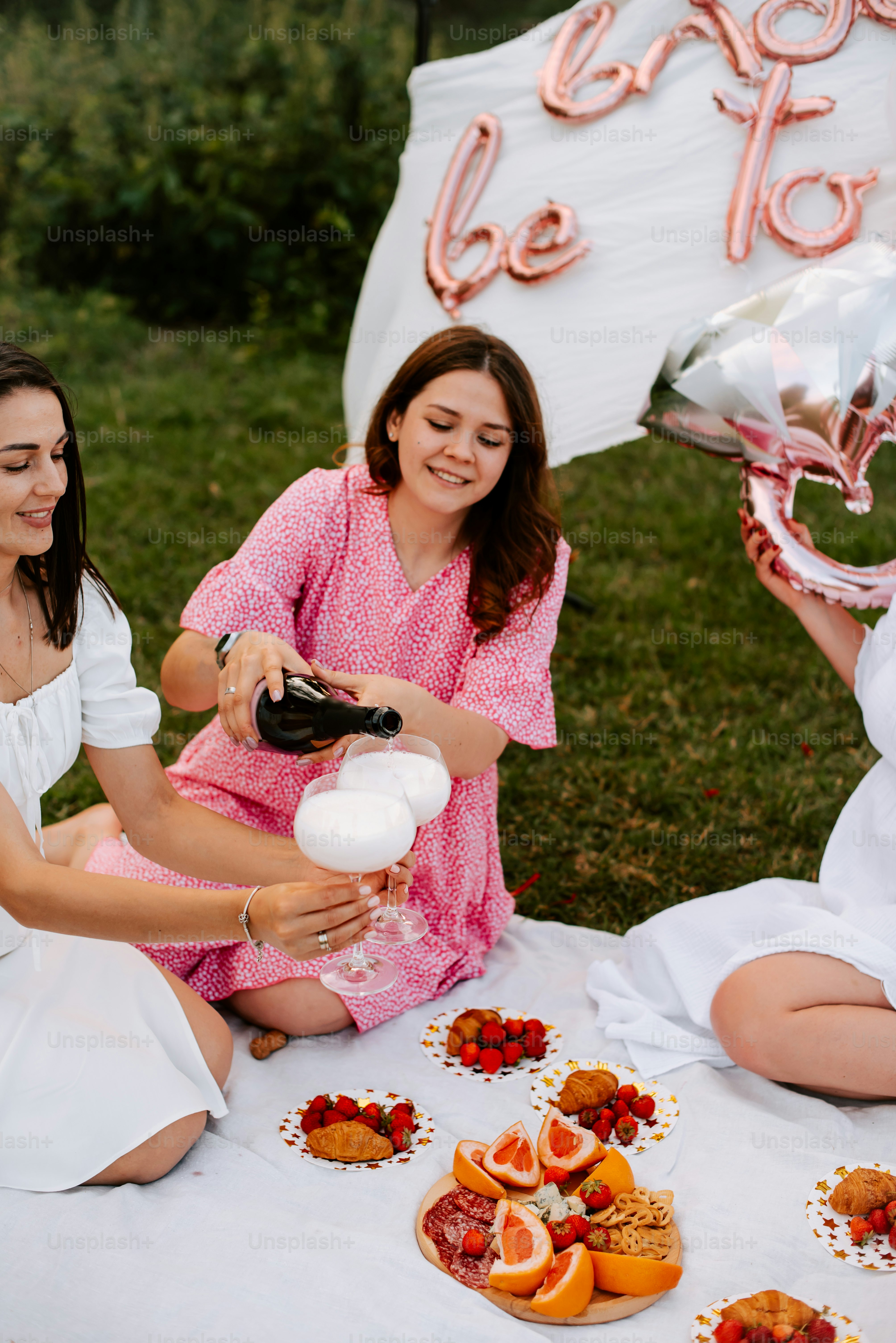 a group of women sitting on top of a grass covered field