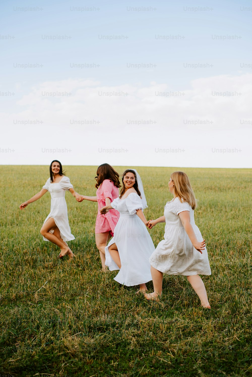 a group of women in white dresses running across a field