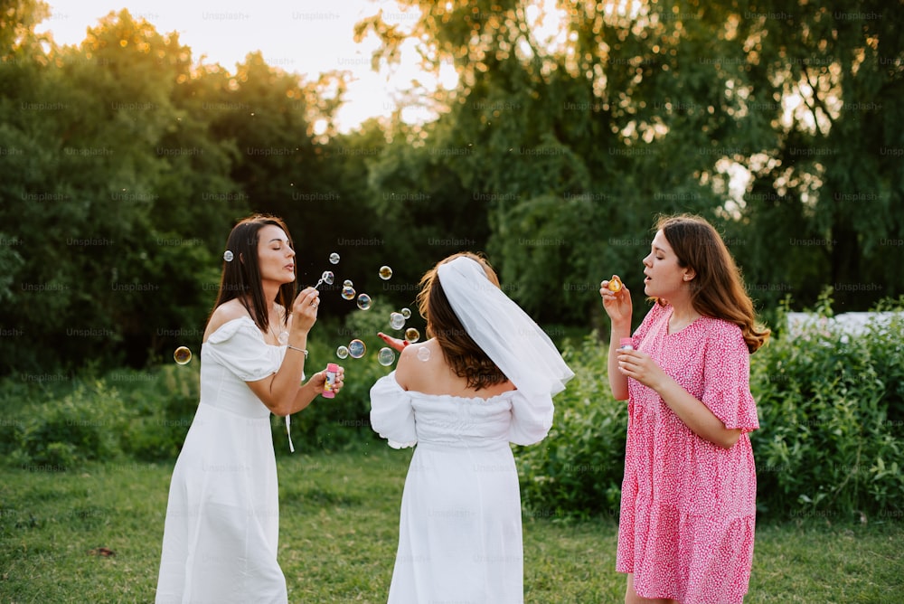 two women in white dresses blowing soap bubbles