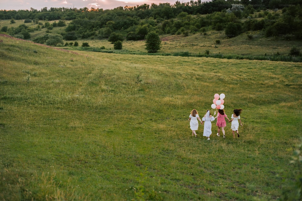 a group of children walking across a lush green field