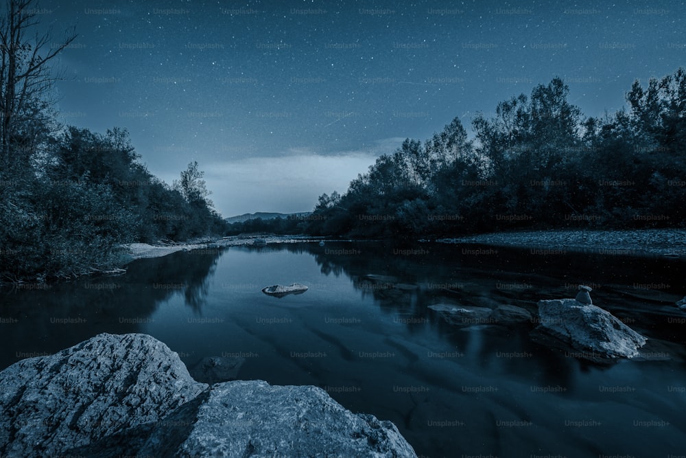 a body of water surrounded by rocks under a night sky