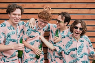 a group of men in matching pajamas holding beer bottles