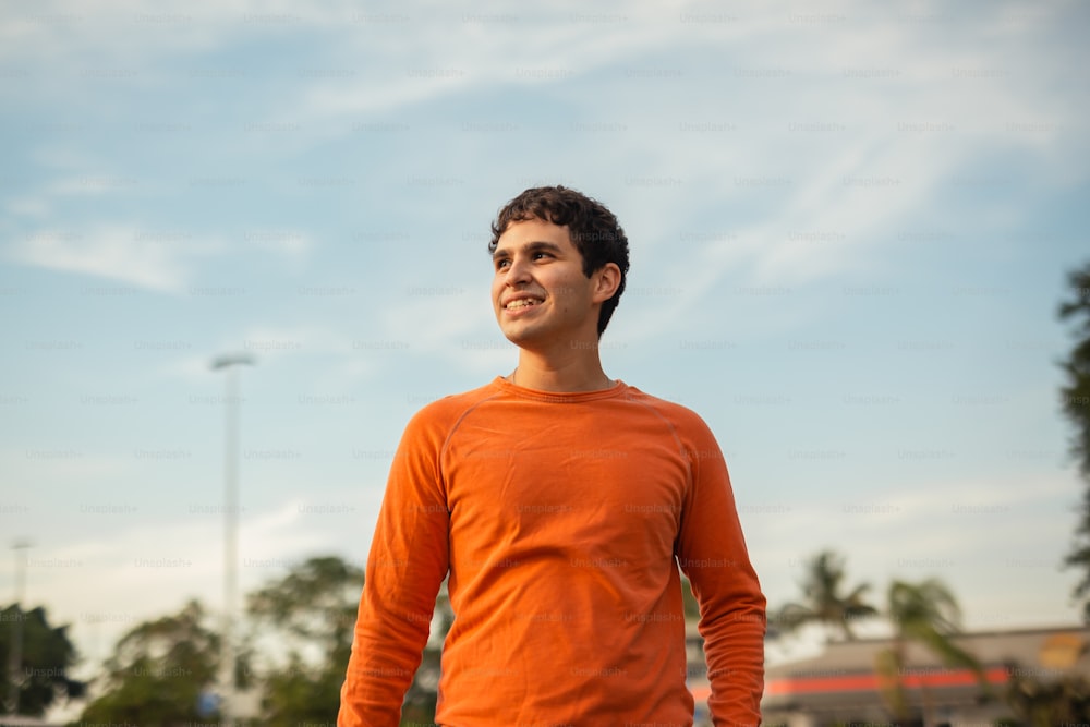 a man in an orange shirt standing in a parking lot