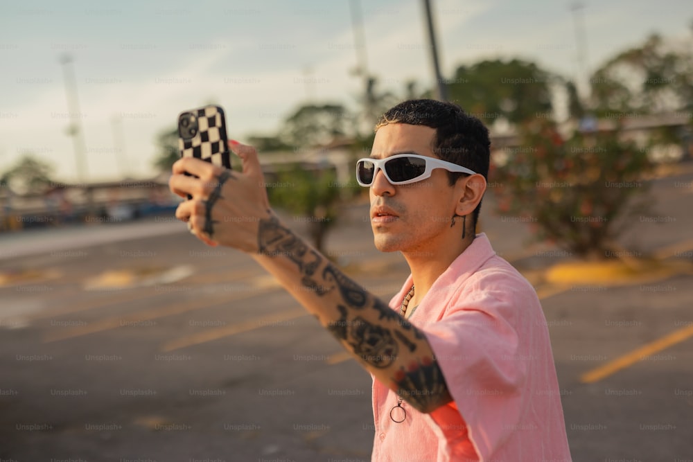 a man in a pink shirt holding up a cell phone