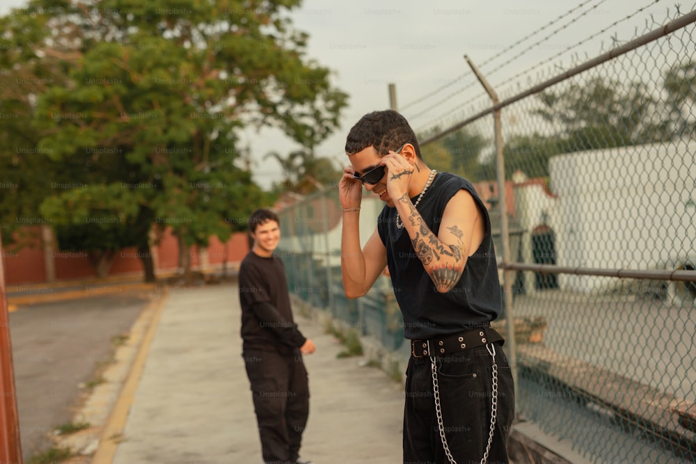 a man standing next to a fence talking on a cell phone