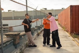 un couple d’hommes debout l’un à côté de l’autre près d’une clôture