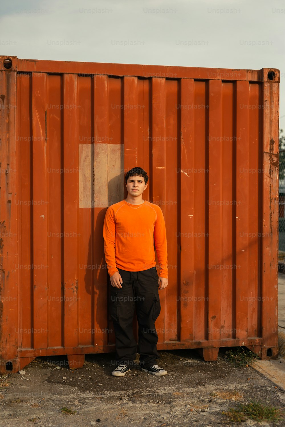 a young man standing in front of a rusted container