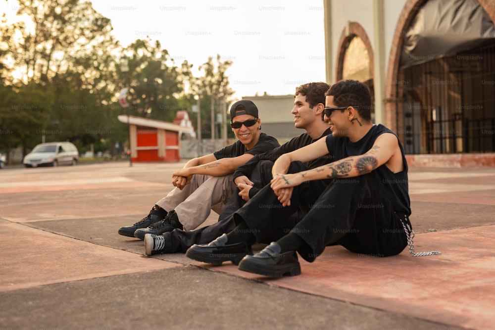 Tres hombres sentados en el suelo frente a un edificio