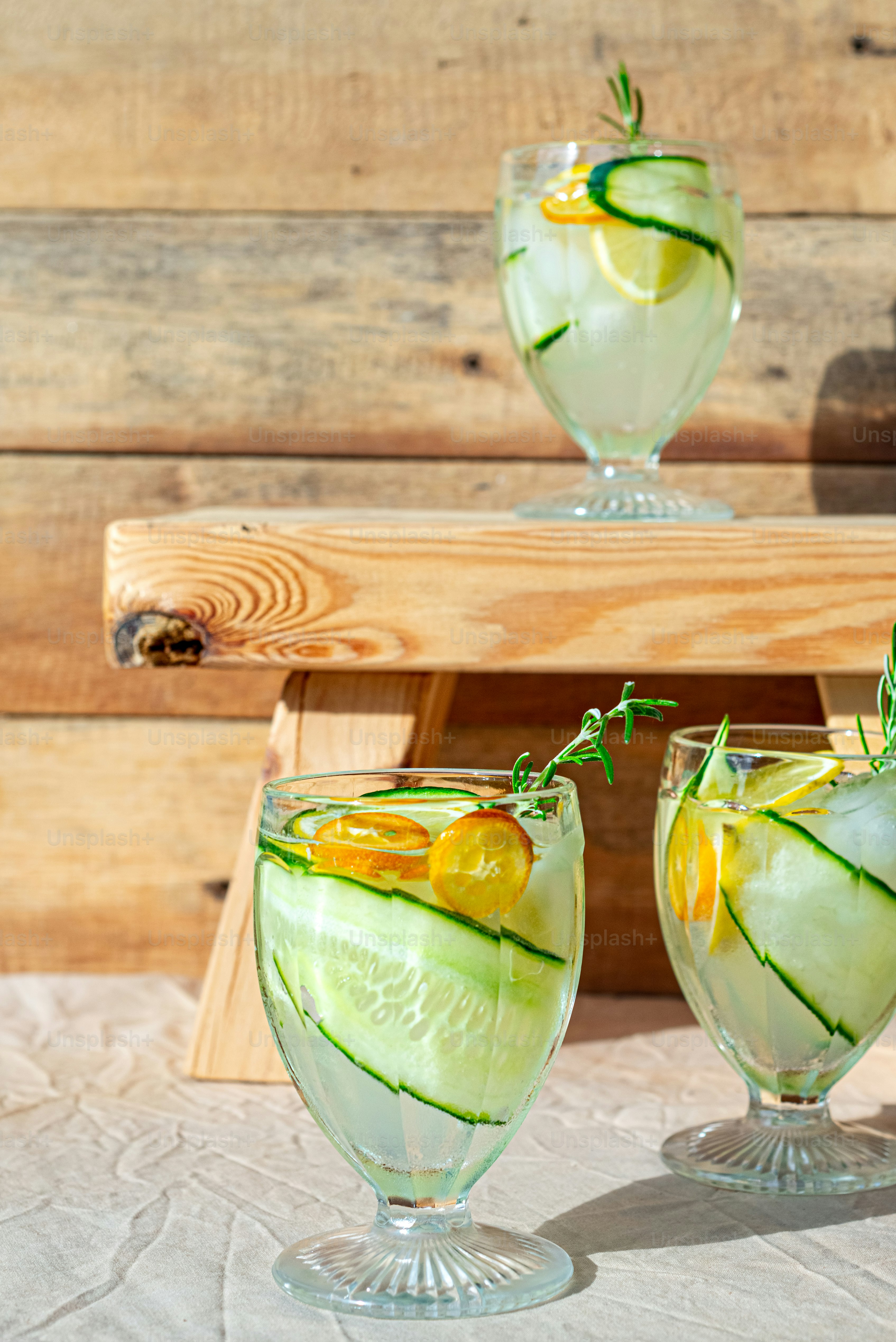 a couple of glasses filled with cucumber and lemonade