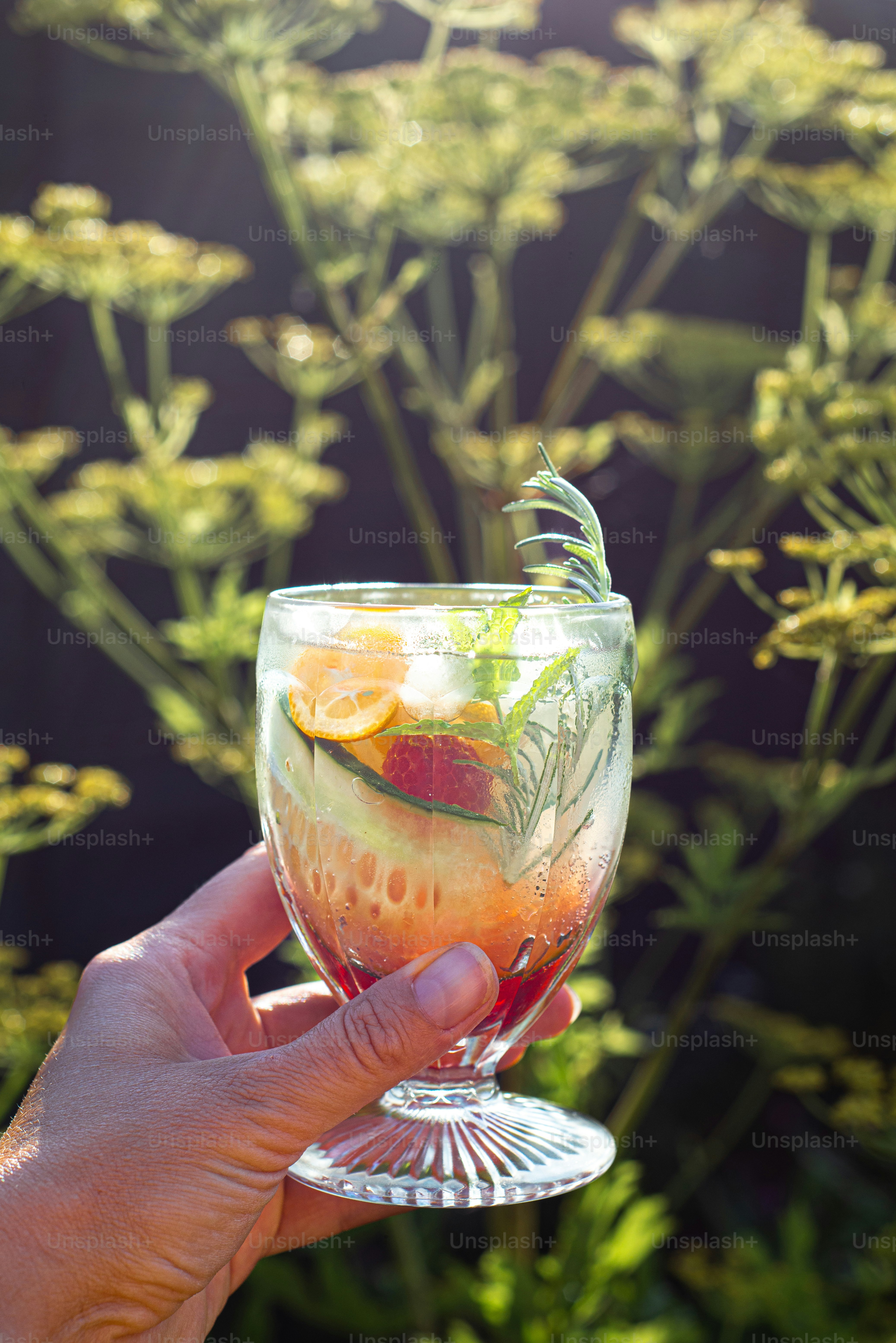 a hand holding a wine glass filled with fruit