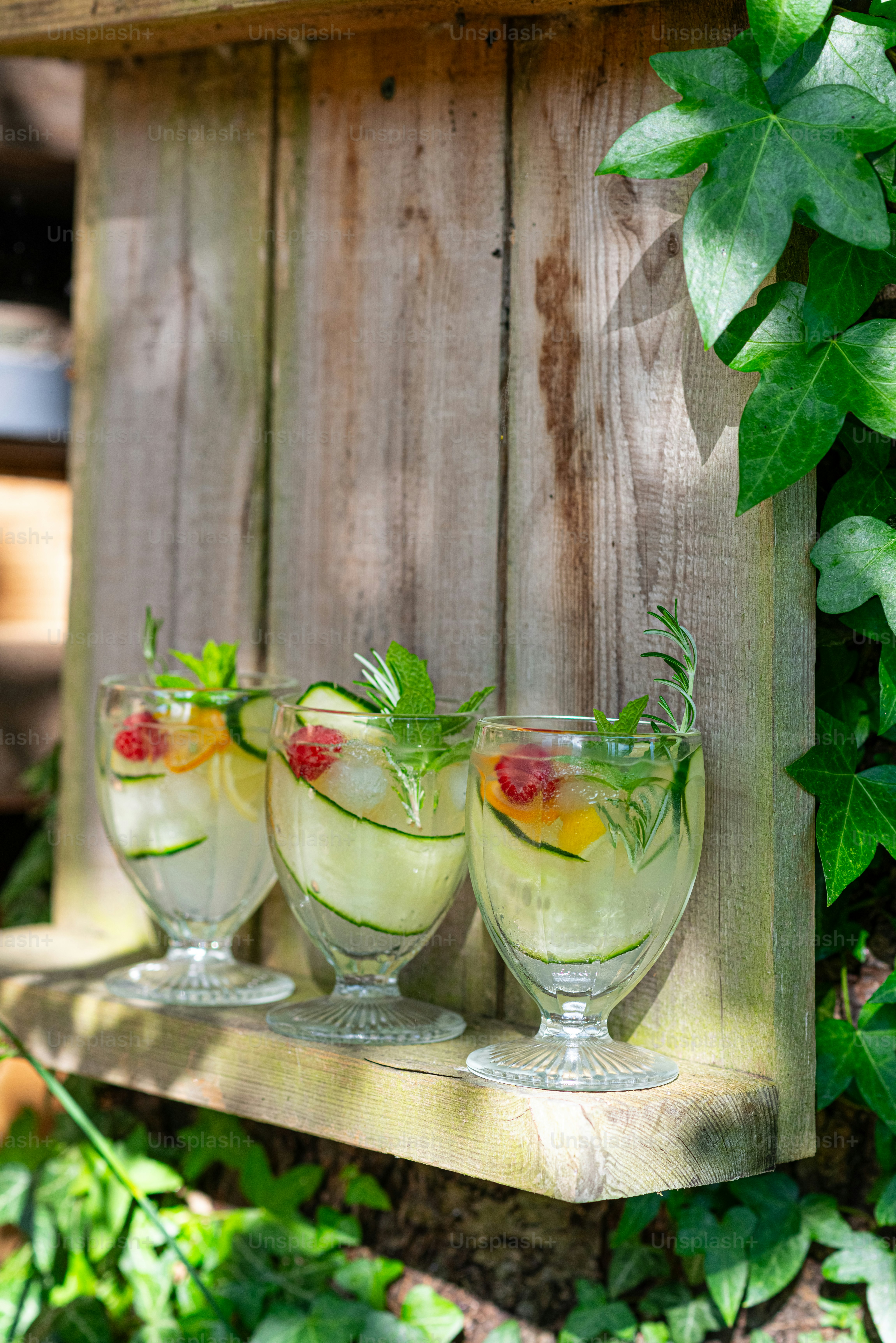 four glasses filled with liquid sitting on a shelf