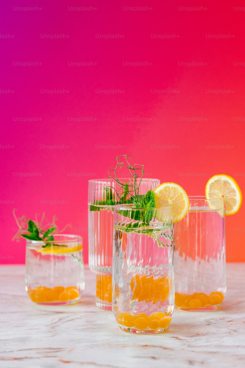 three glasses with lemons and herbs in them
