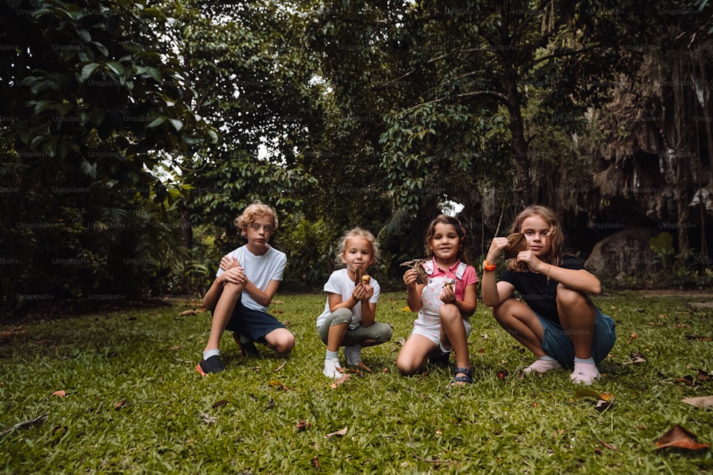 a group of young children sitting on top of a lush green field