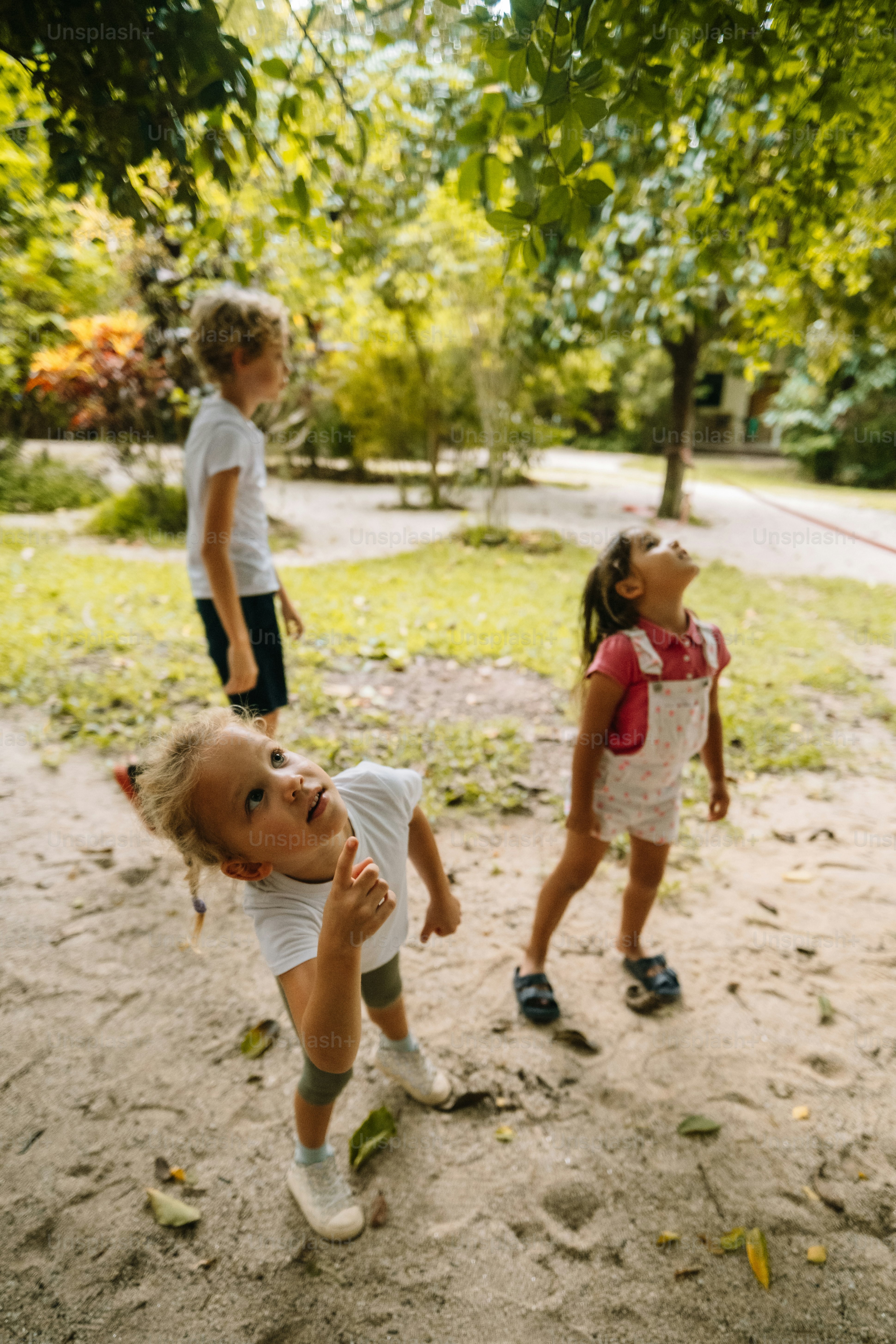 a group of young children standing on top of a dirt field